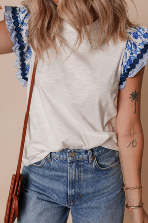 White tee with embroidered blue floral flutter sleeves and ruffled trim