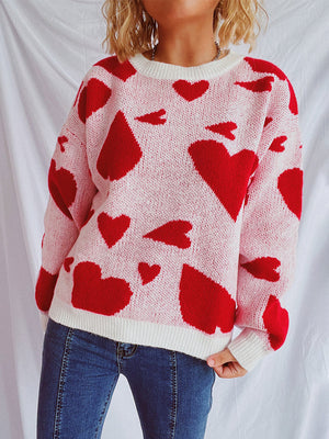 Pink knit sweater with red heart pattern, crew neck, long sleeves, and white trim.