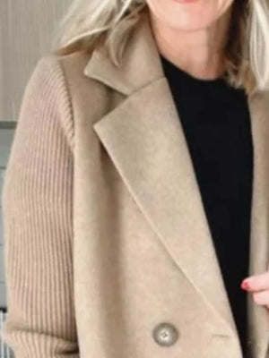 Tan double-breasted trench coat with knit sleeves and a notched lapel.