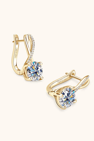 Gold crossover moissanite huggie earrings with diamond accents and a large center stone.