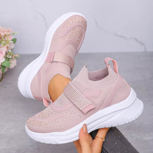 Pink mesh slip-on sneakers with adjustable straps and rhinestone embellishments.