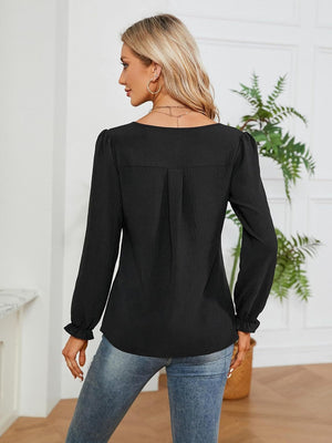 Black textured pleat-front blouse with ruffle cuffs and long sleeves.