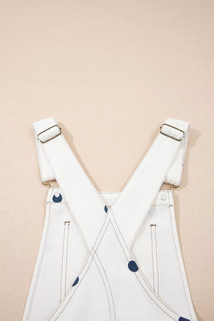 White denim overalls with navy polka dots and adjustable straps.