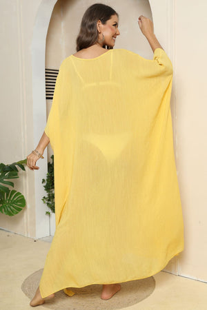Yellow oversized caftan cover-up with side slits, showing bikini underneath.