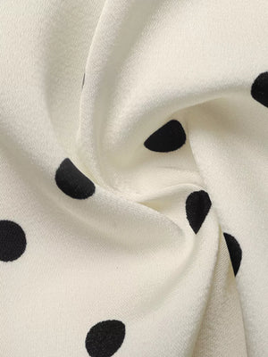 Cream peplum blouse with black polka dots, showing fabric detail.