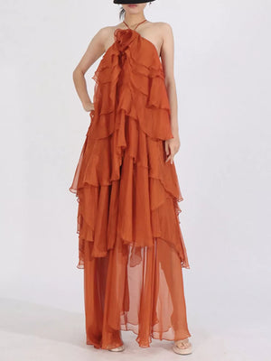 Orange halter maxi dress with cascading ruffles and a floral detail at the neckline.