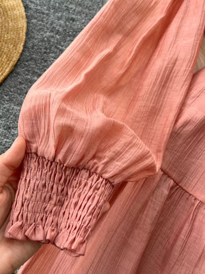 Textured tiered dress in Burnt Coral with smocked cuffs and long sleeves.