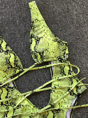Yellow-green snakeskin plunge swimsuit with crisscross straps and cutout detail.