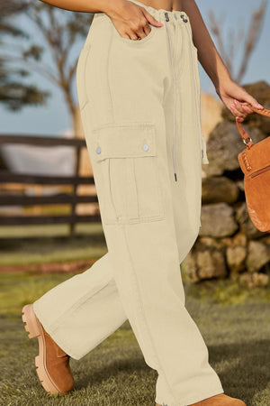 Tan utility denim cargo trousers with drawstring waist and button flap pockets.