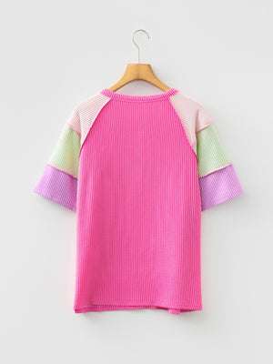 Color block t-shirt with pink, purple, green, and light pink patchwork sleeves and ribbed texture.