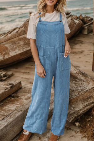 Light blue textured cotton overalls with square pockets and adjustable straps.