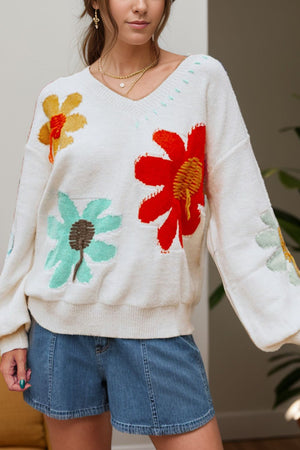 White knit sweater with embroidered floral pattern, V-neck, and long sleeves.
