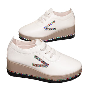 White wedge sneakers with colorful rhinestone embellishments on the side and sole.