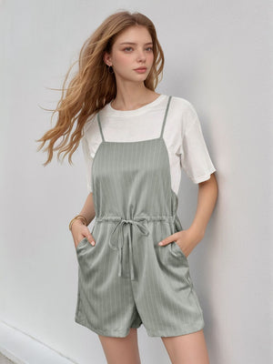 Sage pinstripe romper with adjustable drawstring waist and pockets, styled over a white tee.