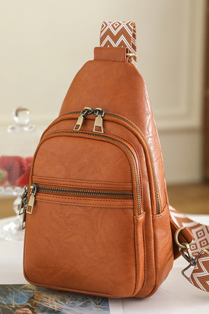 Brown geometric strap sling bag with multiple zippered compartments and gold hardware.
