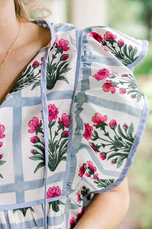 Women's ruffle sleeve blouse with pink floral print and blue trim.