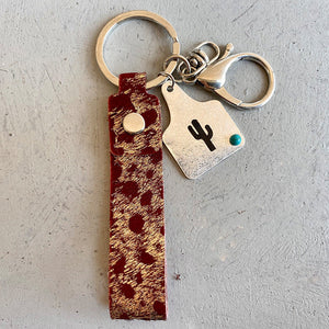 Burgundy cheetah print leather keychain with silver hardware and cactus charm.