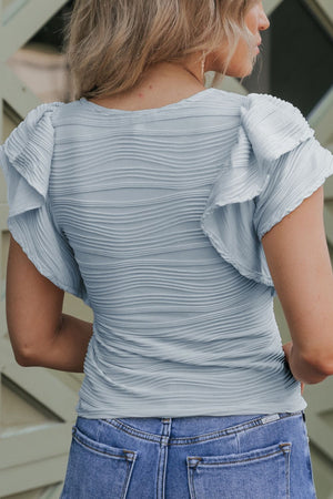 Light blue textured bodysuit with ruffle sleeves and a ruched bodice.