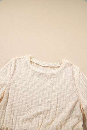 Beige textured blouse with crew neck and ruffle hemline detail