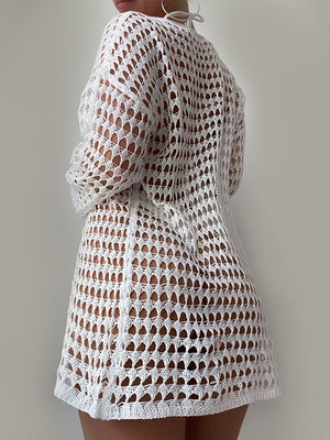 White open-knit beach dress with long sleeves and a boatneck, styled casually.