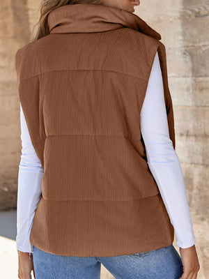 Dark brown ribbed corduroy zip-up vest coat with a high collar, worn over a white long-sleeve shirt.
