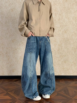 Men's blue washed wide-leg jeans with paneling and a silver chain detail.
