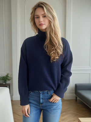 Dark blue relaxed fit turtleneck sweater with ribbed cuffs and hem, styled with jeans.