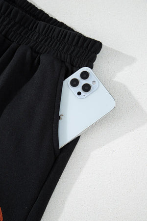 Black cotton sweatpants with elastic waist and phone pocket detail.