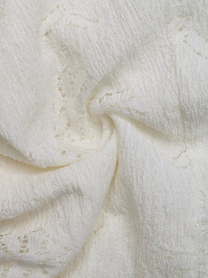 White lace camisole fabric with textured detail and open knit pattern.