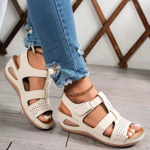 Elegant perforated cream mid-wedge sandals with adjustable straps and comfortable cushioning.