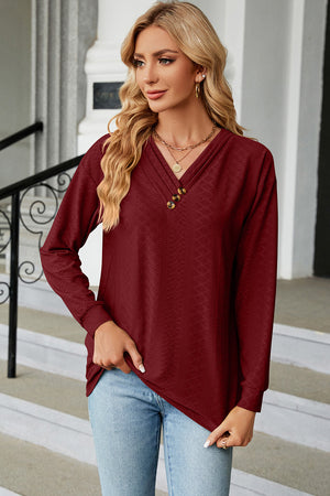 Burgundy textured henley v-neck top with three buttons and long sleeves.