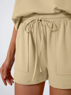 Tan drawstring shorts with elastic waist and patch pockets, part of a loungewear set.