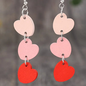 Cascading heartwood dangle earrings in blush pink and red, with three heart charms each.