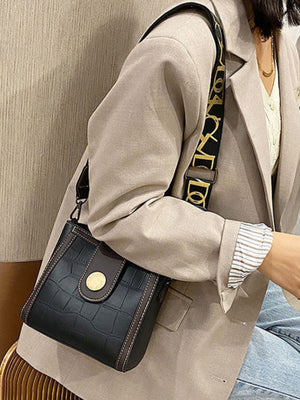 Black crocodile pattern mini crossbody bag with gold button detail and logo strap.