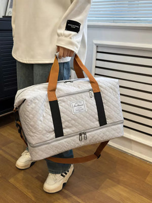 Creamy-white quilted travel duffel bag with brown straps and black accents.