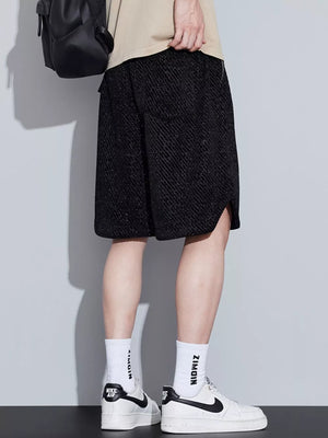 Black textured drawstring shorts with diagonal pattern and side slits.
