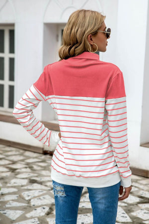 Colorblock stripe turtleneck knit sweater with coral and white stripes.