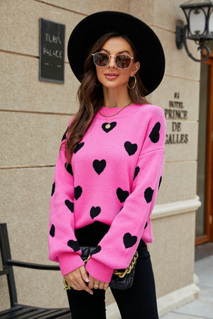 Pink sweater with black hearts, balloon sleeves, and crew neck.