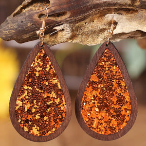Wood-framed teardrop earrings with orange glitter inlay and gold hooks.