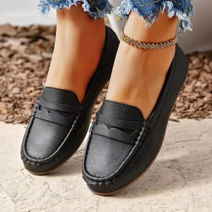 Black leather loafer flats with subtle stitching and a decorative strap detail.