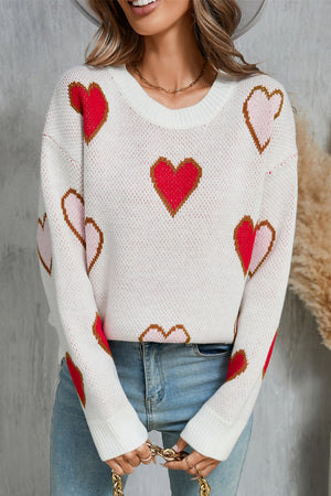 White knit crewneck sweater with allover red, pink, and brown heart motif.