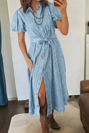 Light blue denim midi dress with puff sleeves, collar, gold buttons, and tie belt.
