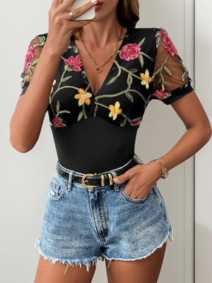 Black bodysuit with embroidered floral mesh sleeves and V-neck.