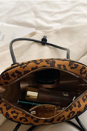 Caramel leopard print barrel bag with black trim and zipper, showing interior makeup.
