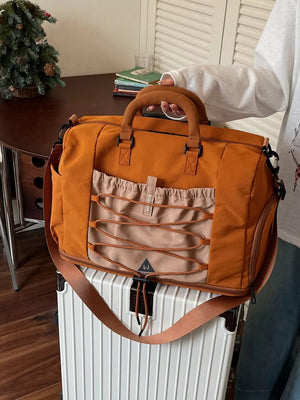 Orange nylon duffel bag with beige front pocket and bungee cord detail.
