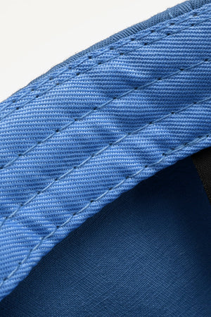 Cobalt blue denim baseball cap detail with raw edge and contrast stitching.