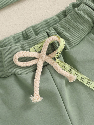 Green cotton baby outfit with drawstring waist and ribbed waistband detail.