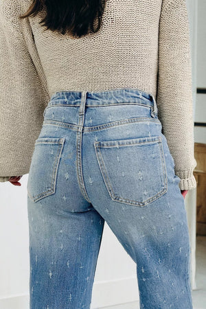 High-rise light wash denim jeans with distressed details and raw hem.
