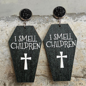Gothic coffin earrings with white text I SMELL CHILDREN and a cross graphic.