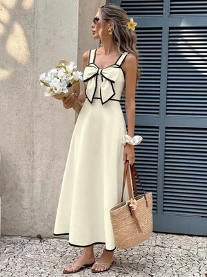 Beige A-line midi dress with black trim and large bow detail on bust.